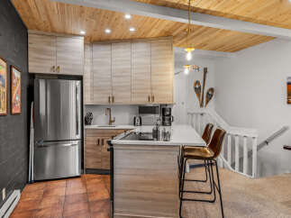 Experience modern mountain living in this beautifully updated kitchen, featuring sleek light wood cabinetry and a stunning waterfall island with bar seating.