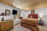 Experience rustic charm in this cozy bedroom, featuring a unique wooden bed frame and a plush window seat overlooking the natural landscape.