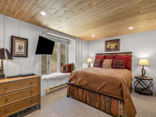 Experience rustic charm in this cozy bedroom, featuring a unique wooden bed frame and a plush window seat overlooking the natural landscape.