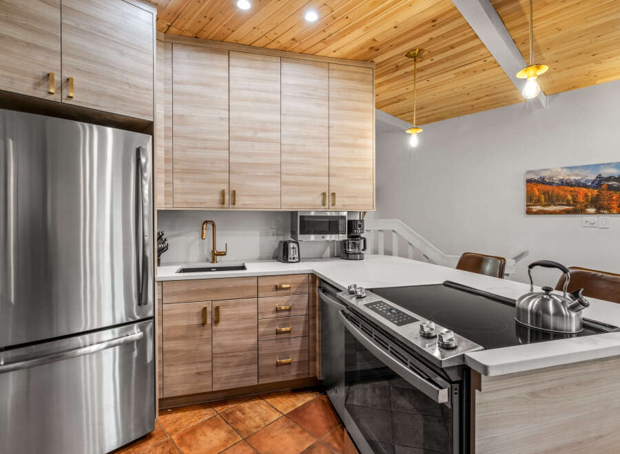 Experience modern living in this stunning kitchen featuring sleek, light wood cabinetry and a durable quartz countertop.