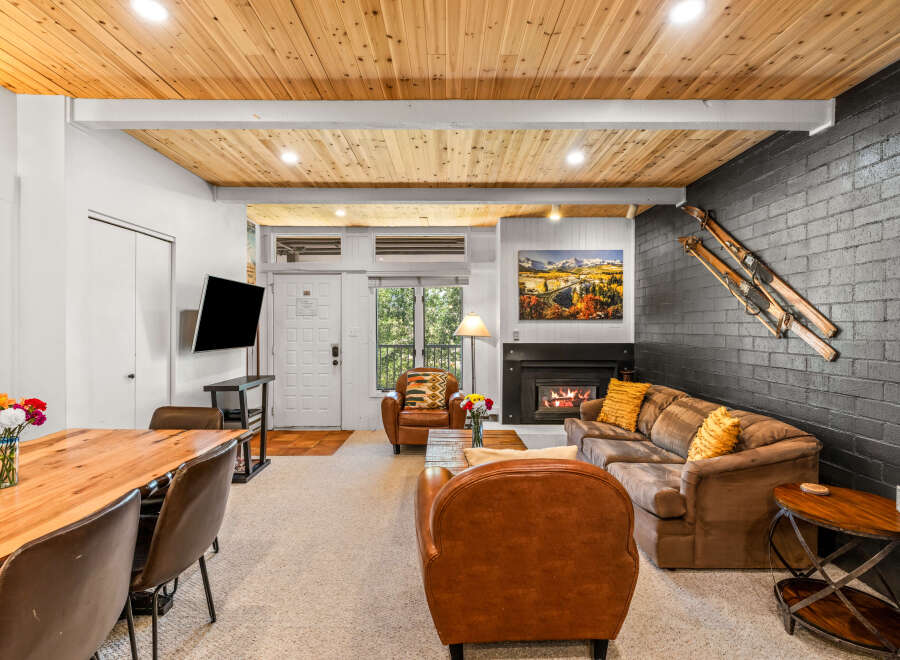Experience cozy living in this inviting space featuring a warm wood-paneled ceiling and a charming fireplace.