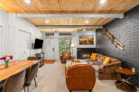 Experience cozy living in this inviting space featuring a warm wood-paneled ceiling and a charming fireplace.