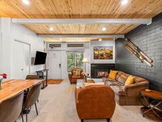 Experience cozy living in this inviting space featuring a warm wood-paneled ceiling and a charming fireplace.