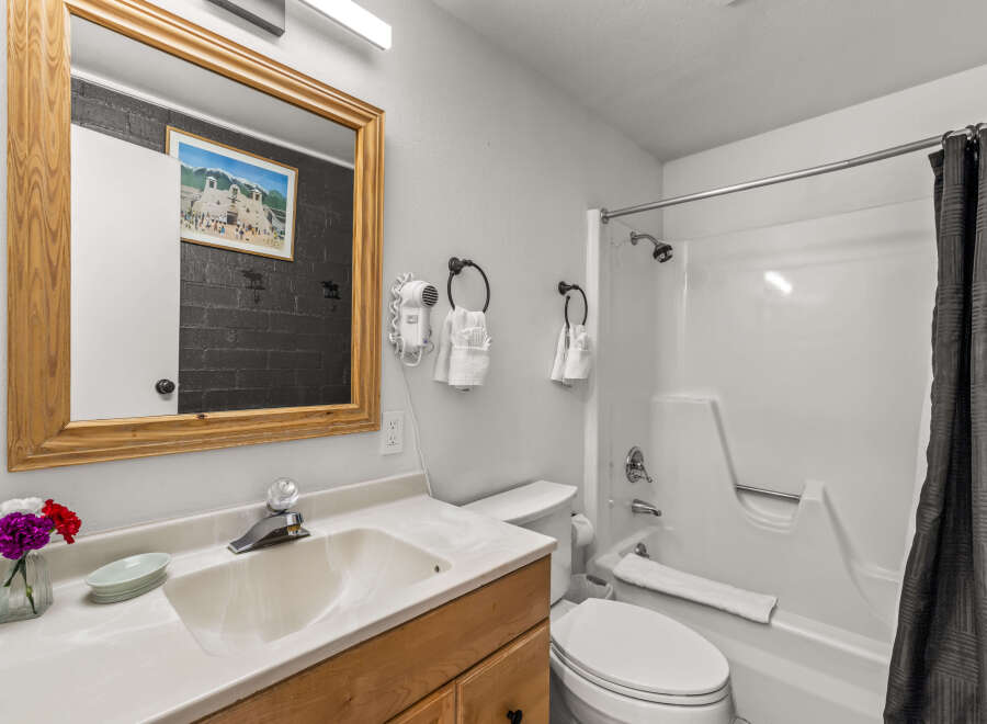 This charming bathroom features a spacious vanity with a wooden cabinet, a clean white sink, and a large mirror with a wooden frame.