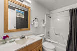 This charming bathroom features a spacious vanity with a wooden cabinet, a clean white sink, and a large mirror with a wooden frame.