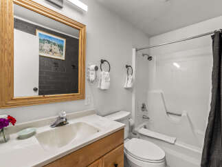 This charming bathroom features a spacious vanity with a wooden cabinet, a clean white sink, and a large mirror with a wooden frame.