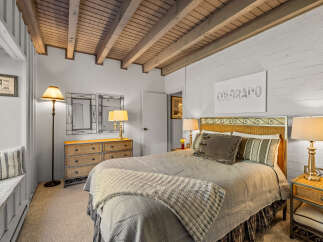 Experience cozy mountain living in this charming bedroom featuring a comfortable bed with a wicker headboard and plush bedding.