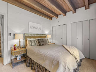 Discover this charming bedroom featuring a cozy queen-size bed with a wicker headboard, perfect for restful nights.
