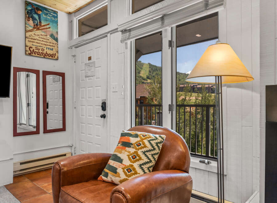 Experience the charm of Steamboat Springs with this inviting living space, featuring a cozy leather armchair adorned with a decorative pillow.