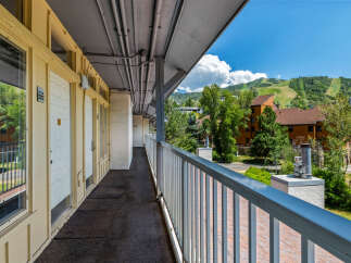 Enjoy the mountain views from this charming property's exterior walkway, offering a glimpse of the ski slopes and surrounding greenery.