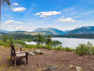 Experience breathtaking panoramic views from this stunning property, featuring a serene lake and majestic mountains.