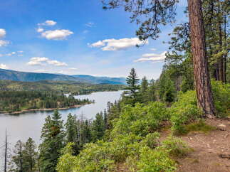 Discover breathtaking lakefront living with this stunning property offering panoramic views of a serene lake and lush, rolling hills.