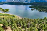 Discover breathtaking natural beauty with this stunning aerial view of a serene lake surrounded by lush green forests and majestic mountains.