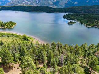 Discover breathtaking natural beauty with this stunning aerial view of a serene lake surrounded by lush green forests and majestic mountains.