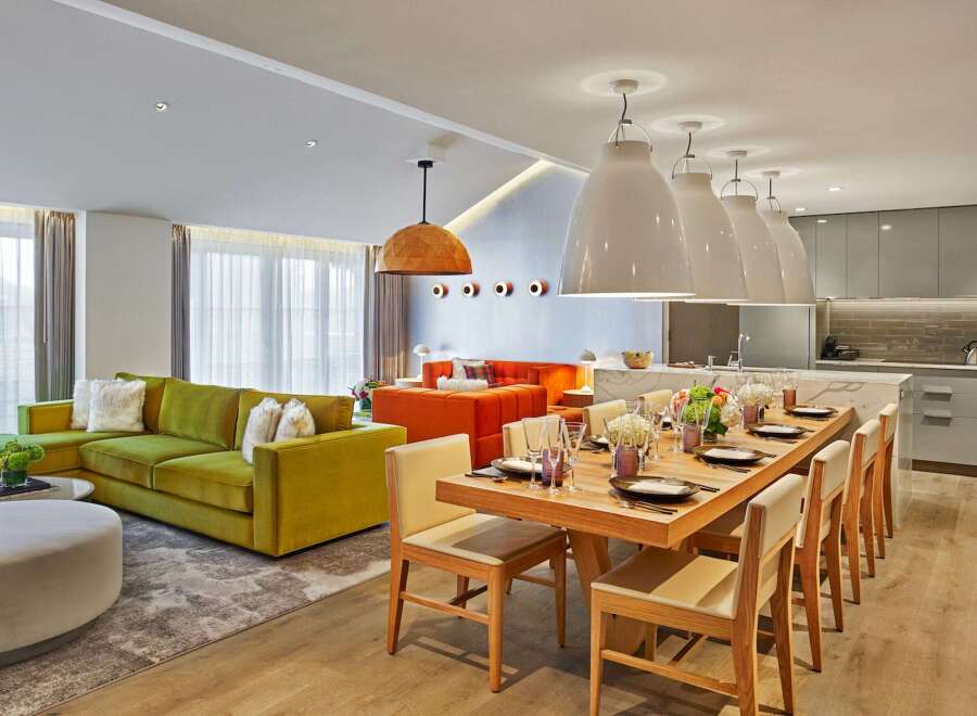 Experience modern luxury in this spacious open-plan living area, featuring a vibrant green sectional sofa and a striking orange sofa.