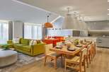 Experience modern luxury in this spacious open-plan living area, featuring a vibrant green sectional sofa and a striking orange sofa.