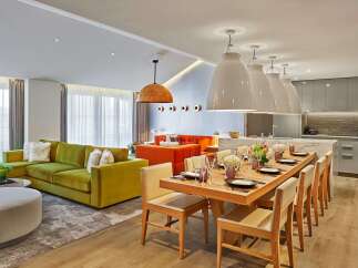 Experience modern luxury in this spacious open-plan living area, featuring a vibrant green sectional sofa and a striking orange sofa.