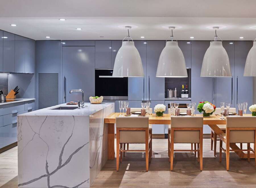 Experience modern luxury in this stunning kitchen and dining area, featuring sleek grey cabinetry and a striking marble island.