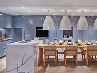 Experience modern luxury in this stunning kitchen and dining area, featuring sleek grey cabinetry and a striking marble island.