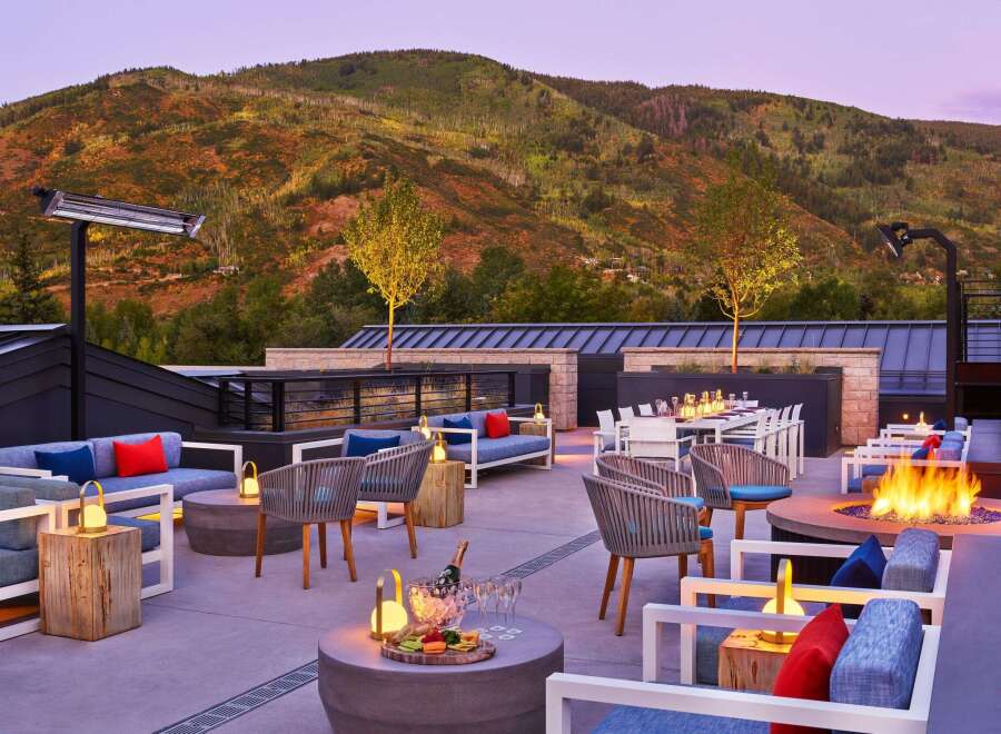 Experience luxury outdoor living with this stunning rooftop patio, featuring comfortable seating areas, a cozy fire pit, and breathtaking mountain views.