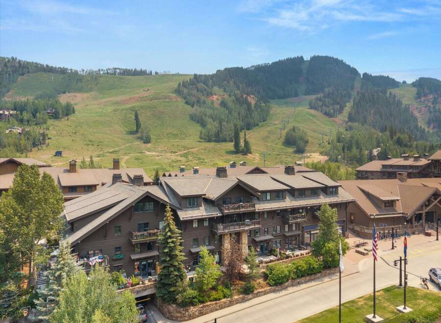 Experience luxury mountain living in this stunning property, featuring a grand lodge-style building with multiple balconies and large windows.