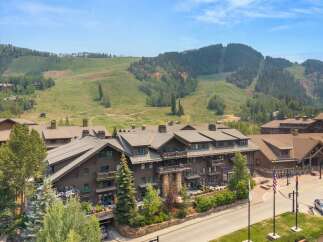 Experience luxury mountain living in this stunning property, featuring a grand lodge-style building with multiple balconies and large windows.