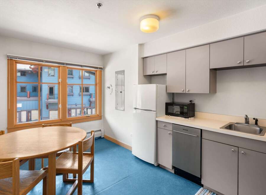 This charming kitchen and dining area features a round wooden dining table with chairs, perfect for intimate meals.