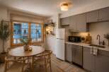 This charming studio apartment features a cozy dining area with a round wooden table and chairs, perfect for intimate meals.