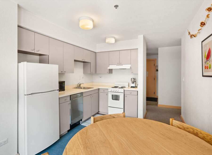 Discover this charming kitchen featuring a full-sized refrigerator, a convenient dishwasher, and a modern stove with an overhead vent.
