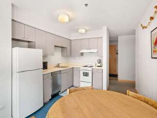 Discover this charming kitchen featuring a full-sized refrigerator, a convenient dishwasher, and a modern stove with an overhead vent.