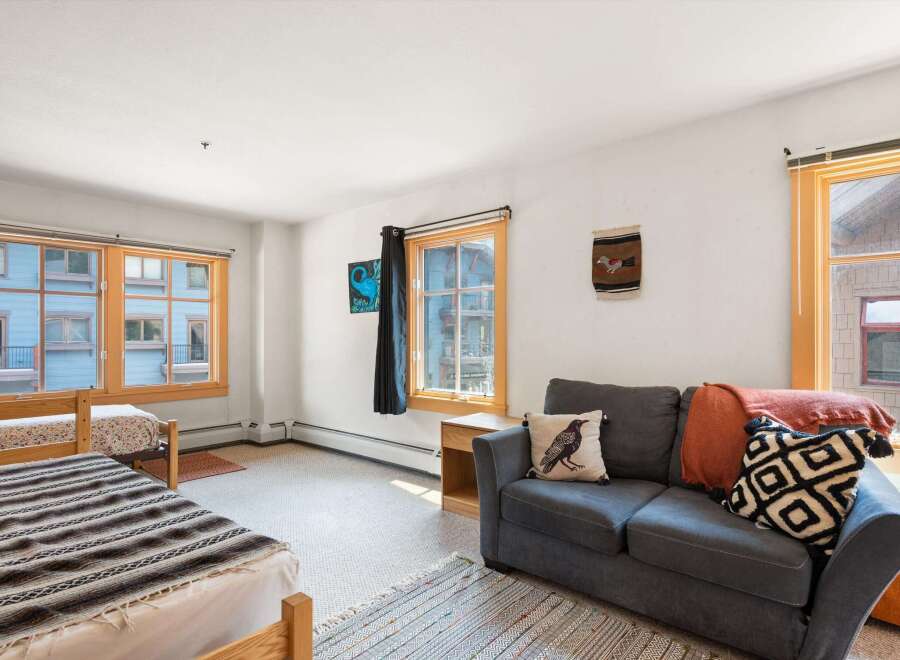 This cozy living space features two comfortable beds and a plush sofa, perfect for relaxing after a day of adventure.