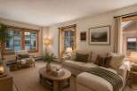 Experience cozy living in this inviting living room, featuring a plush sectional sofa adorned with decorative pillows and a warm green throw blanket.