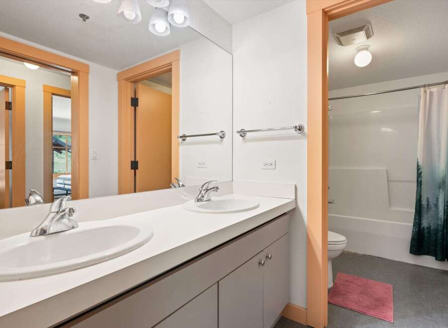 This bright and airy bathroom features a spacious double vanity with modern chrome fixtures, perfect for busy mornings.