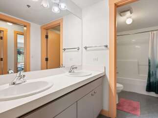 This bright and airy bathroom features a spacious double vanity with modern chrome fixtures, perfect for busy mornings.