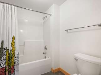This bathroom features a clean white bathtub and shower combo, complemented by a stylish shower curtain with a cactus print.