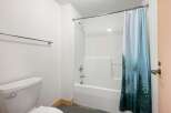 This bathroom features a clean white bathtub and shower combo, complemented by a stylish shower curtain with a forest motif.
