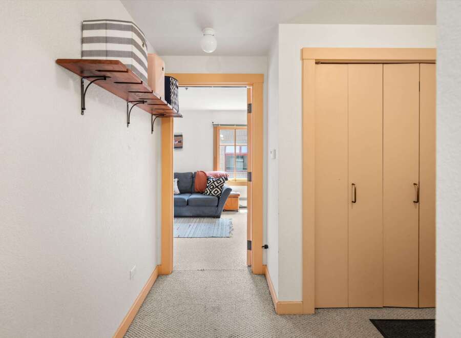 Step into this inviting hallway featuring a charming wooden shelf with decorative baskets, perfect for storage and display.