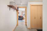 Step into this inviting hallway featuring a charming wooden shelf with decorative baskets, perfect for storage and display.