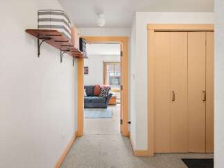 Step into this inviting hallway featuring a charming wooden shelf with decorative baskets, perfect for storage and display.