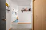 This hallway features a dark gray door with a brass handle and lock, leading into a carpeted area.