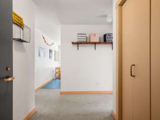 This hallway features a dark gray door with a brass handle and lock, leading into a carpeted area.