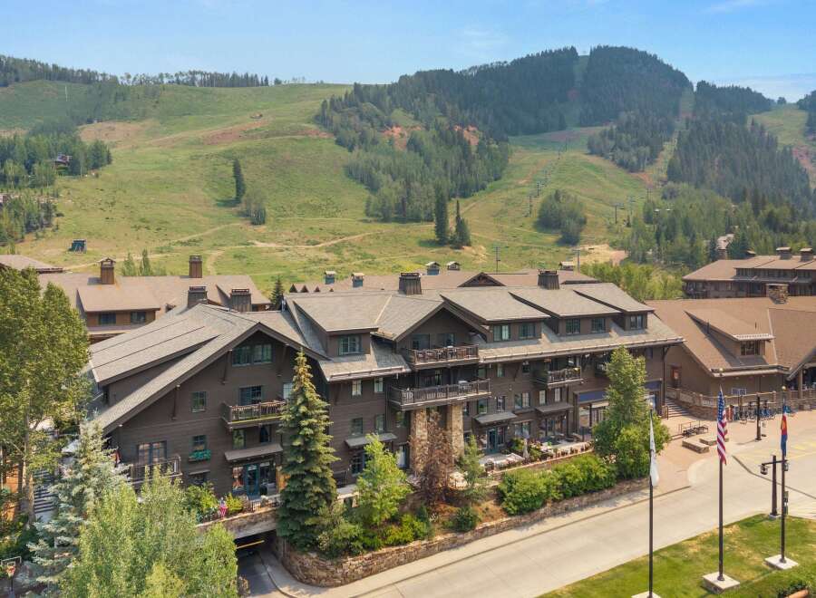 Experience luxury mountain living in this stunning property, featuring a grand lodge-style building with multiple balconies and expansive windows.