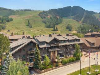 Experience luxury mountain living in this stunning property, featuring a grand lodge-style building with multiple balconies and expansive windows.