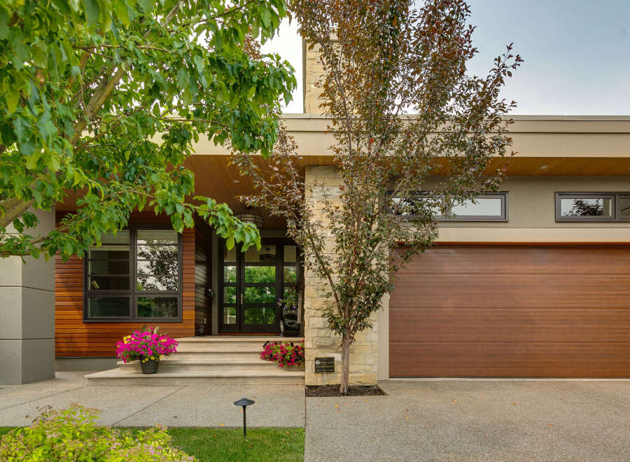 Discover modern luxury with this stunning home featuring a striking facade of wood, stone, and stucco.