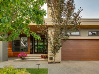 Discover modern luxury with this stunning home featuring a striking facade of wood, stone, and stucco.