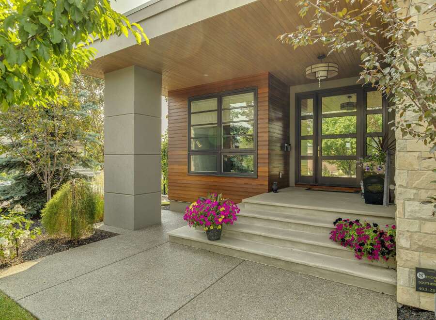 Experience modern luxury with this stunning home featuring a sleek facade of wood and stone accents.