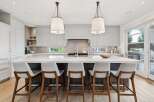 Experience luxury in this stunning modern kitchen, featuring a spacious waterfall island with ample seating.