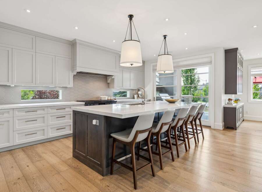 Experience luxury in this stunning modern kitchen, featuring sleek light gray cabinetry and a spacious island with a waterfall countertop.