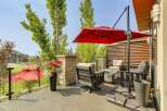 Enjoy outdoor living with this stunning patio featuring comfortable seating, a modern fire pit, and a vibrant red umbrella for shade.