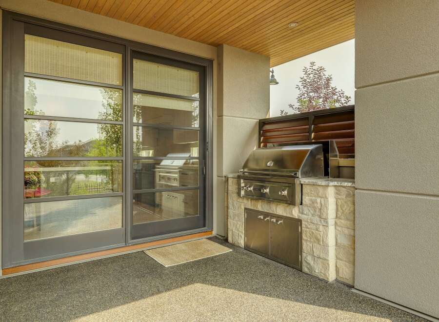 Experience seamless indoor-outdoor living with this modern covered patio, featuring a sleek sliding glass door that opens to a gourmet outdoor kitchen.